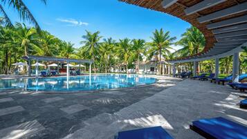 A pool area with lounge chairs and palm trees.