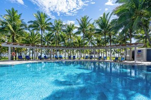 Ein Pool mit blauem Wasser, umgeben von Palmen und blauen Liegestühlen.