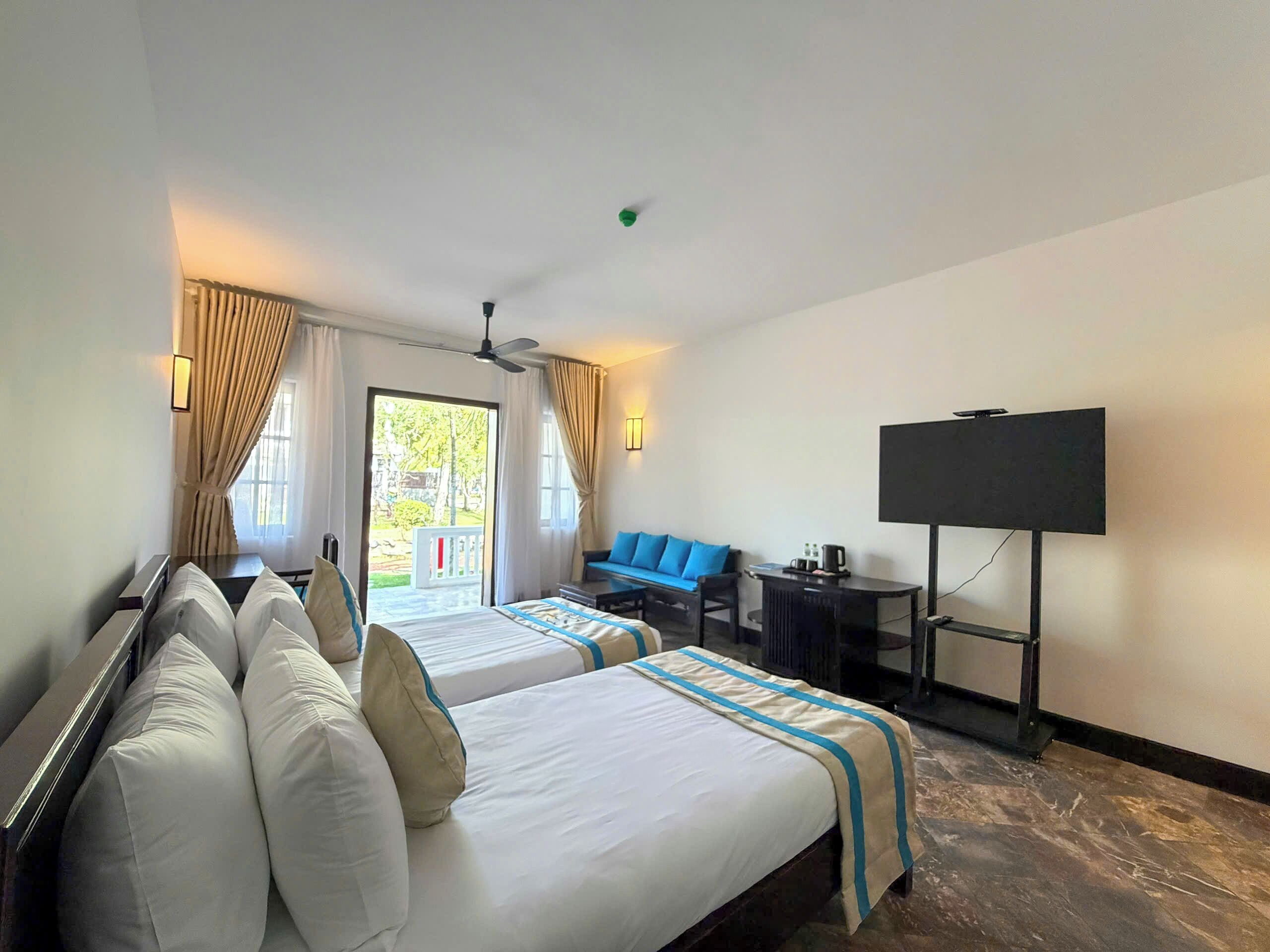 Une chambre d’hôtel avec deux lits, un bureau, une chaise, une télévision et une vue sur l’extérieur.