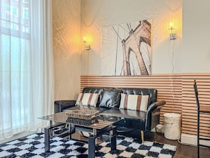 A modern living room with a leather sofa, glass coffee table, and a large abstract painting on the wall.