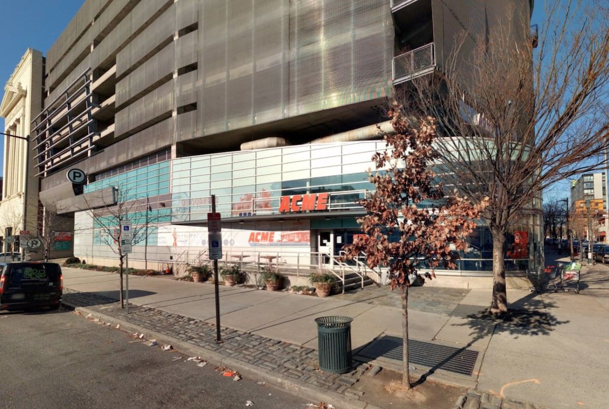 A multi-story building with a large glass facade, a parking sign, and a tree with pink blossoms.