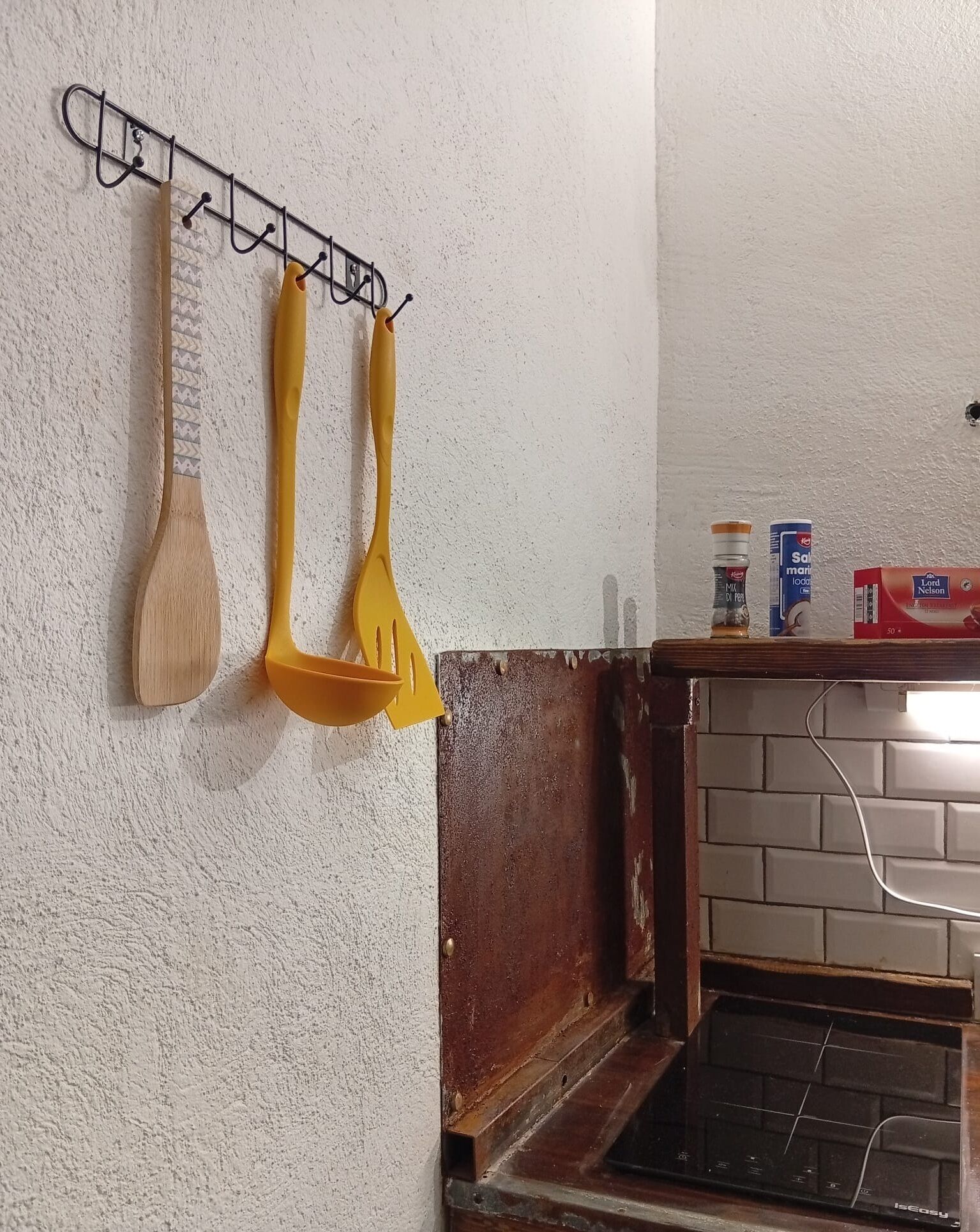 Una cocina con un colgador para utensilios, una pared de ladrillo y un mueble de madera abajo.