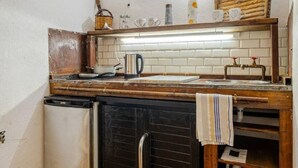 Une cuisine compacte dotée d’un plan de travail en bois, d’un petit réfrigérateur et d’un pare-feu en carreaux.