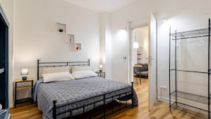 Une chambre à coucher comprenant un lit, des tables de chevet, une armoire et une petite étagère avec quelques objets.