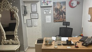 Una reception con un bancone in legno, un grande specchio, certificati incorniciati, una sveglia e una insegna a parete.
