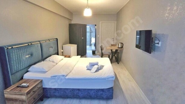 Una camera da letto con un letto, un comodino e una televisione appesa al muro.