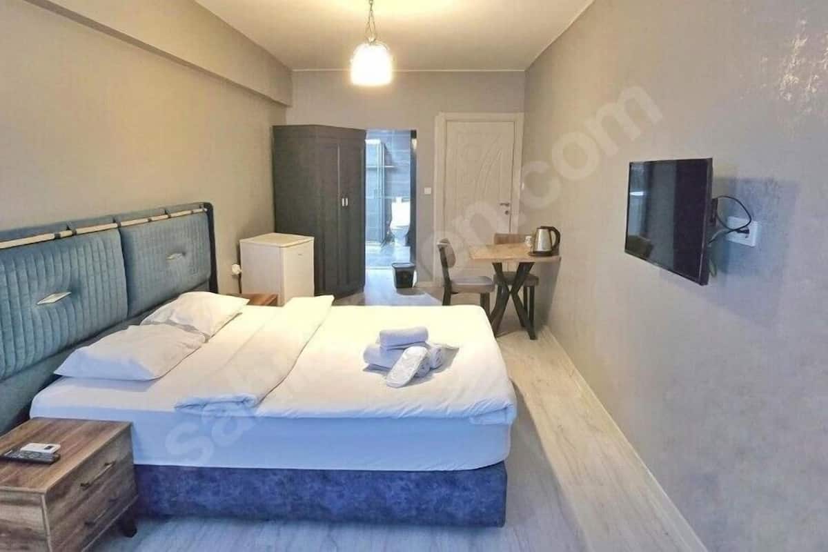 A bedroom with a bed, bedside table, and a television on the wall.