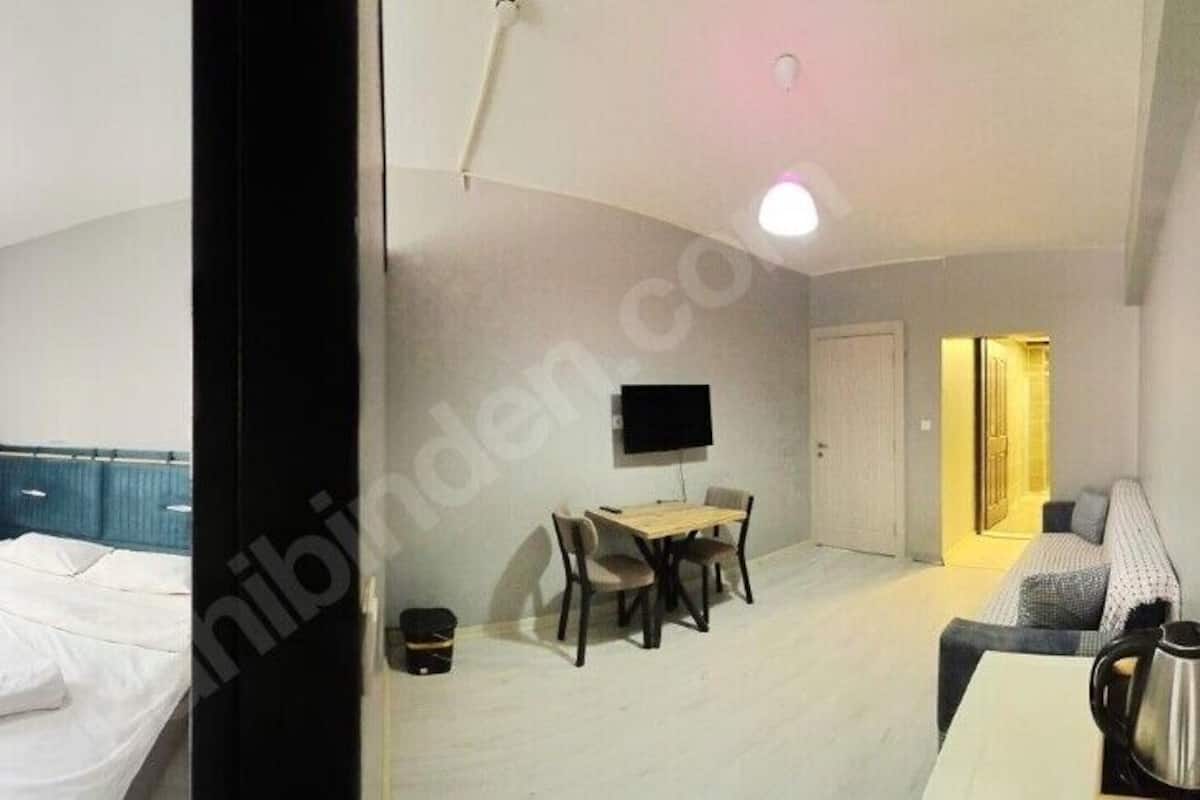 A hotel room with a bed, a desk, a chair, a TV, and a coffee maker.