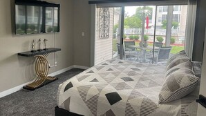Un dormitorio con cama, televisor montado en la pared, ventilador de techo y vistas al exterior.