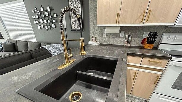 Una cocina moderna con un lavamanos negro, electrodomésticos de acero inoxidable y armarios de madera.