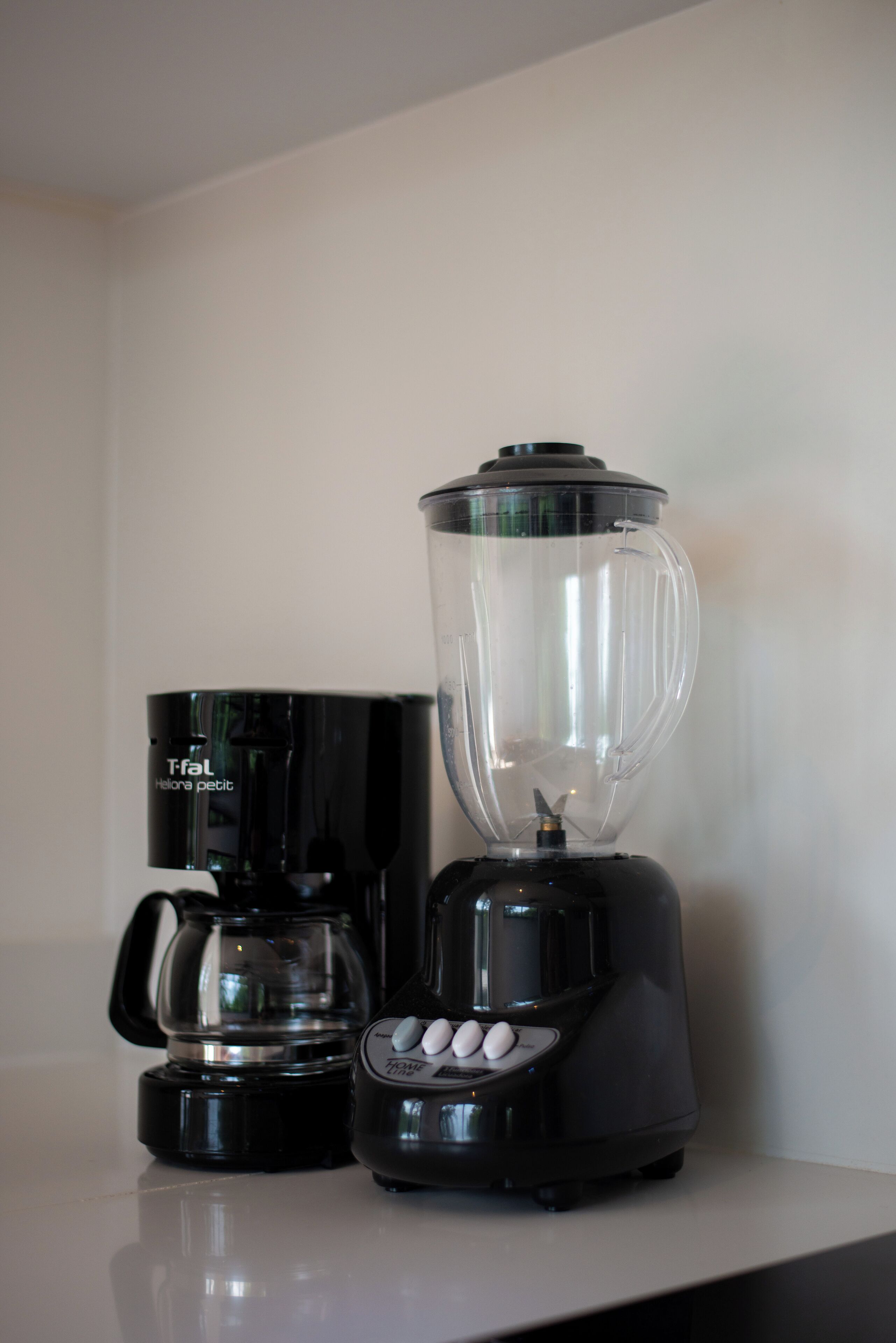 Een koffiezetapparaat en een blender op een aanrecht.