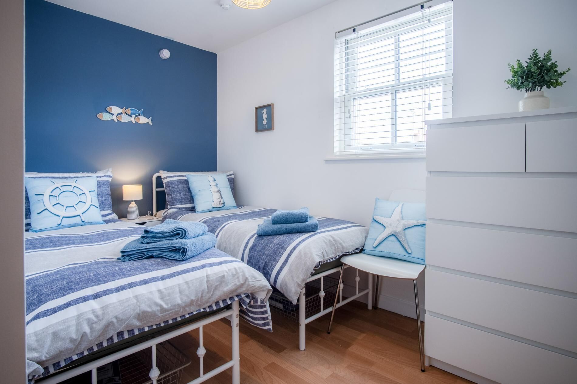 A bedroom with two beds, a desk, and a wardrobe.