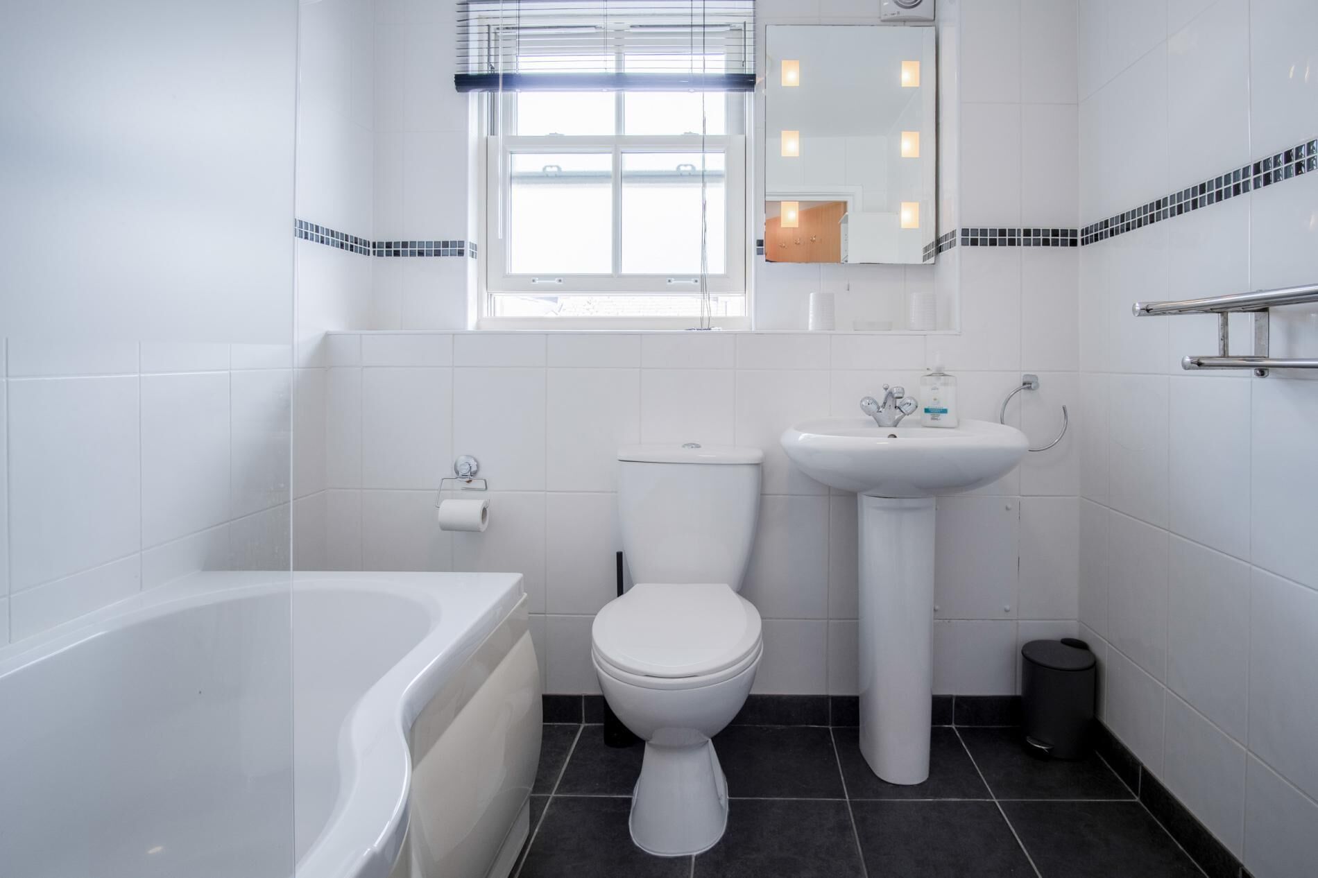 A modern bathroom with a bathtub, toilet, and sink.