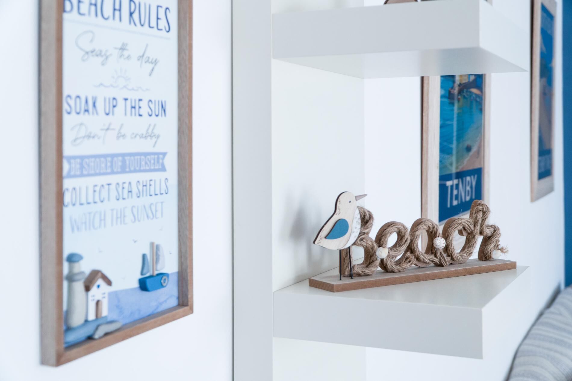A wall with a framed sign listing beach rules and a decorative bird sculpture.