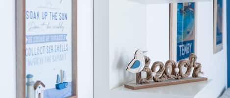 A wall with a framed sign listing beach rules and a decorative bird sculpture.