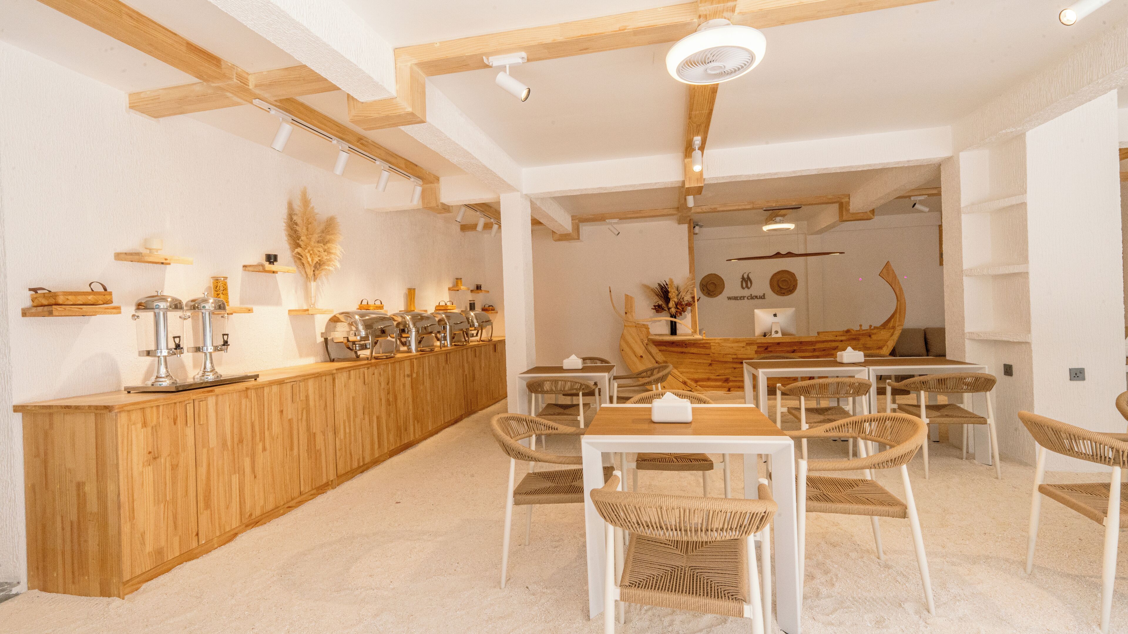 Un restaurante con mostrador de madera, sillas blancas y decoración de pared con forma de barco.