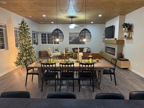 A dining area with a wooden table, black chairs, and a Christmas tree.
