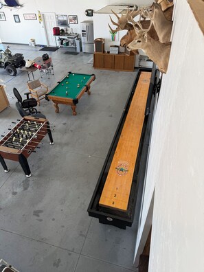 A room with a pool table, a foosball table, and a shuffleboard table.
