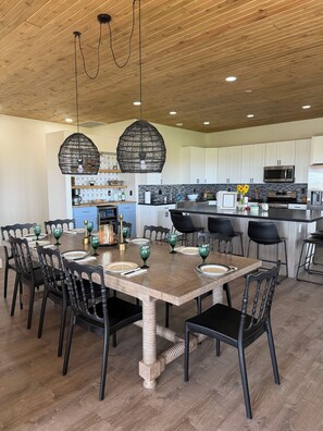 Een moderne keuken met witte kasten, een centraal eiland en een eethoek met een houten tafel en stoelen.