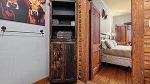 Une pièce rustique avec une armoire en bois, un lit et un tableau représentant des vaches.
