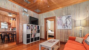 Un salon chaleureux avec un plafond en bois, un canapé, une table basse et une bibliothèque.