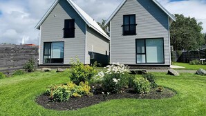 Dos casas modernas de una sola planta con techos a dos aguas y grandes ventanales.