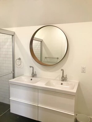 Une salle de bain avec deux lavabos, un miroir rond et un porte-serviettes.