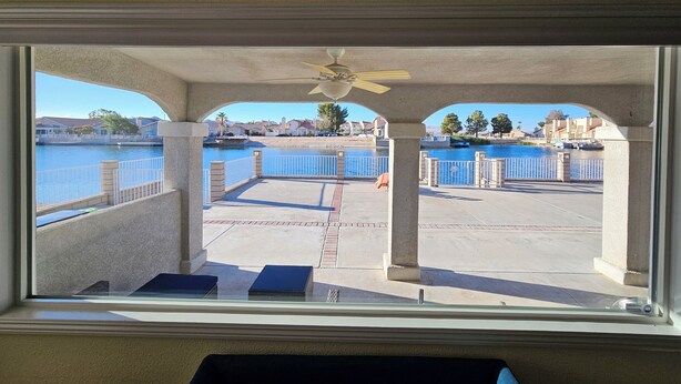 Vista desde una habitación con un ventanal grande que da a una zona costera con piscina y un paseo peatonal.