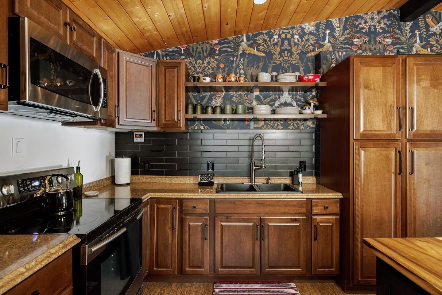 A kitchen with wooden cabinets, a stainless steel range, a black tiled backsplash, and a wooden countertop.