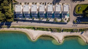 An aerial view of a coastal hotel with multiple balconies, a beachside promenade, and a clear view of the turquoise sea. - Luxury Villa Lunea with Pool I (Trogir)