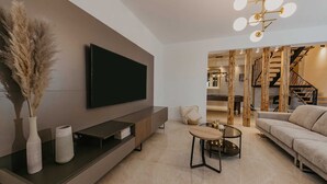 A modern living room with a flat-screen TV, a sofa, a coffee table, and a staircase leading to an upper level. - Villa Del Tempo with Pool (Seget Donji)