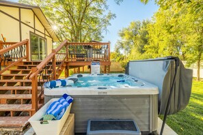 A hot tub with a wooden deck and stairs, a covered area, and a notice sign.