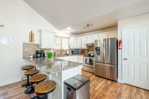 A modern kitchen with a central island, stainless steel appliances, and a seating area with stools.