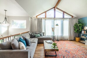 A spacious living room with a large gray sofa, a coffee table, and a patterned rug.