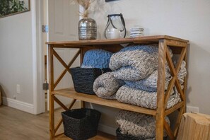 A wooden shelf with folded blankets and a basket.