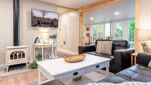 Una sala de estar acogedora con chimenea, un sofá cómodo, una mesa de centro y un televisor montado en la pared.