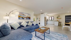 A modern living room with a sofa, a coffee table, and a painting on the wall.