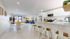 A modern kitchen with white cabinetry, a central island, and bar stools.