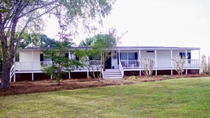 A two-story house with a porch, a small front yard, and a tree. - Relaxing Country Getaway – Pet Friendly, Close to Greenville & Spartanburg (Greer)