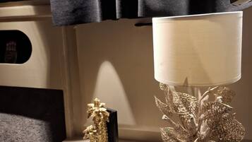 Et natbord med en lampe, en dekorativ guldfigur og en sort genstand på væggen.