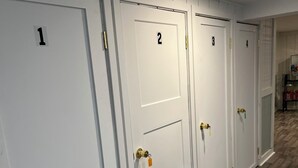 A row of white doors numbered 1 to 4, with brass handles and keys, in a hallway with wooden flooring.