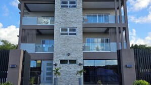 Un immeuble à plusieurs étages doté d’une façade centrale en pierre, de balcons et de grandes fenêtres.