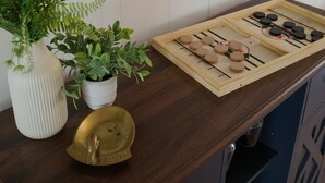 A wooden console table with a mirror, two potted plants, a brass tray, and a tea set. - Riverfront Retreat on Perquimans: Cozy Fire Pit, Golf Minutes Away, Serene Views (Hertford)