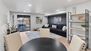 A modern living room with a black sofa, a round table, and a bookshelf. - The House Between 2 Canyons (Cottonwood Heights)