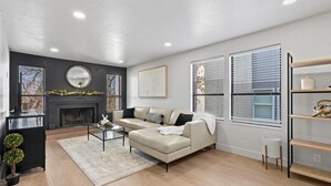 A modern living room with a fireplace, a sofa, a coffee table, and a bookshelf. - The House Between 2 Canyons (Cottonwood Heights)
