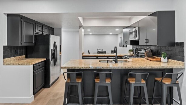 A modern kitchen with a central island, bar stools, and a built-in oven. - The House Between 2 Canyons (Cottonwood Heights)