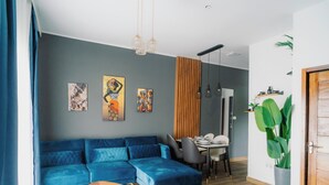 Una sala moderna con un sofá seccional azul, una mesa de comedor y una planta verde grande.