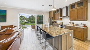 A modern kitchen with granite countertops, wooden cabinets, and a large island. - Tropical Siesta Key Getaway | Heated Private Pool + Fire Pit | 4BR Sleeps 10 | Minutes to Siesta Beach & Village! (Siesta Key)