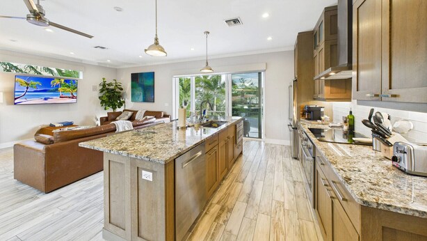 A modern kitchen with granite countertops, wooden cabinets, and stainless steel appliances. - Tropical Siesta Key Getaway | Heated Private Pool + Fire Pit | 4BR Sleeps 10 | Minutes to Siesta Beach & Village! (Siesta Key)