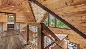 Ein Holzinnenraum mit hoher Decke, einer Treppe und großen Fenstern.